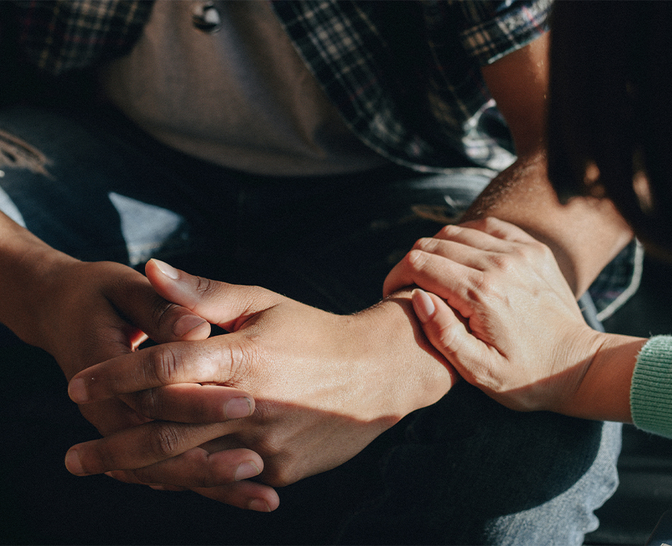 A woman places her hand on a man’s forearm as a gesture of support.
