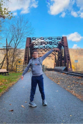 Young boy standing on a road in front of a bridge