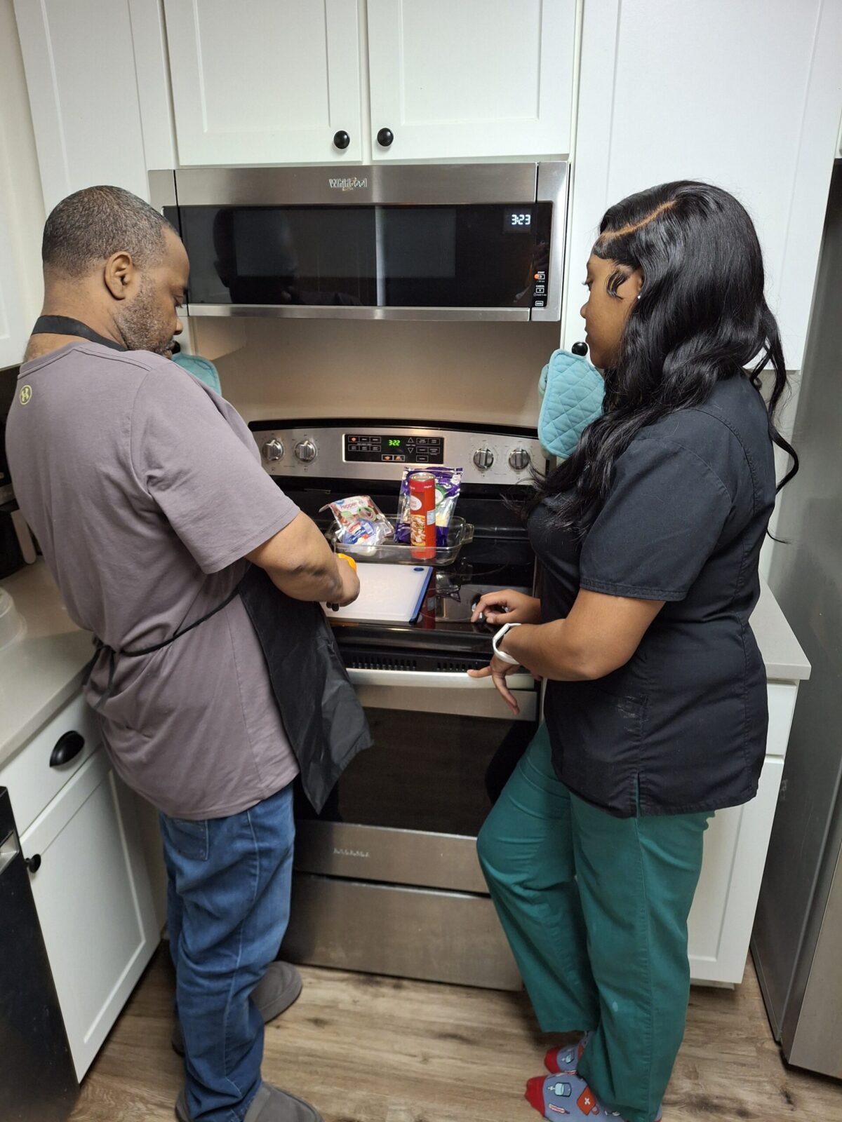 man and woman standing facing a kitchen stove